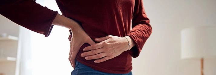 Chiropractic Tustin CA body Person holding lower back, indicating pain or discomfort.